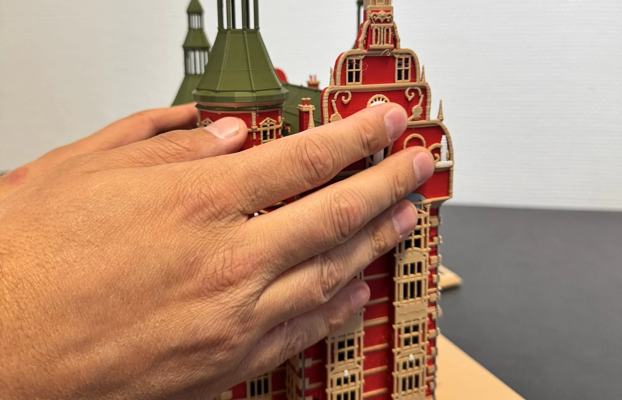 Edis's hand reads the gable of a coloured 3D-printed model of Rosenborg Castle: red walls, sand-coloured window frames and green copper towers with golden spires.